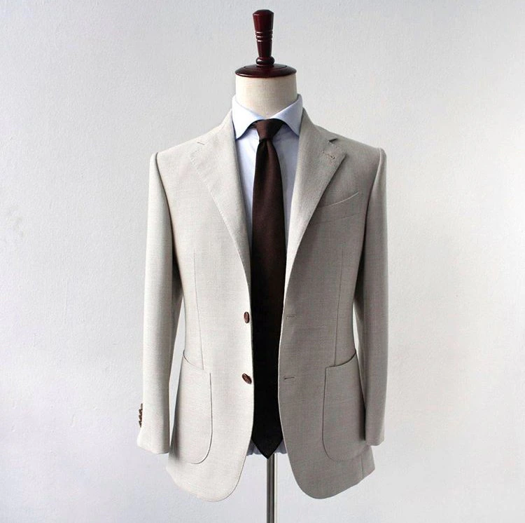 A mannequin dressed in a light gray suit jacket, white shirt, and dark brown tie.